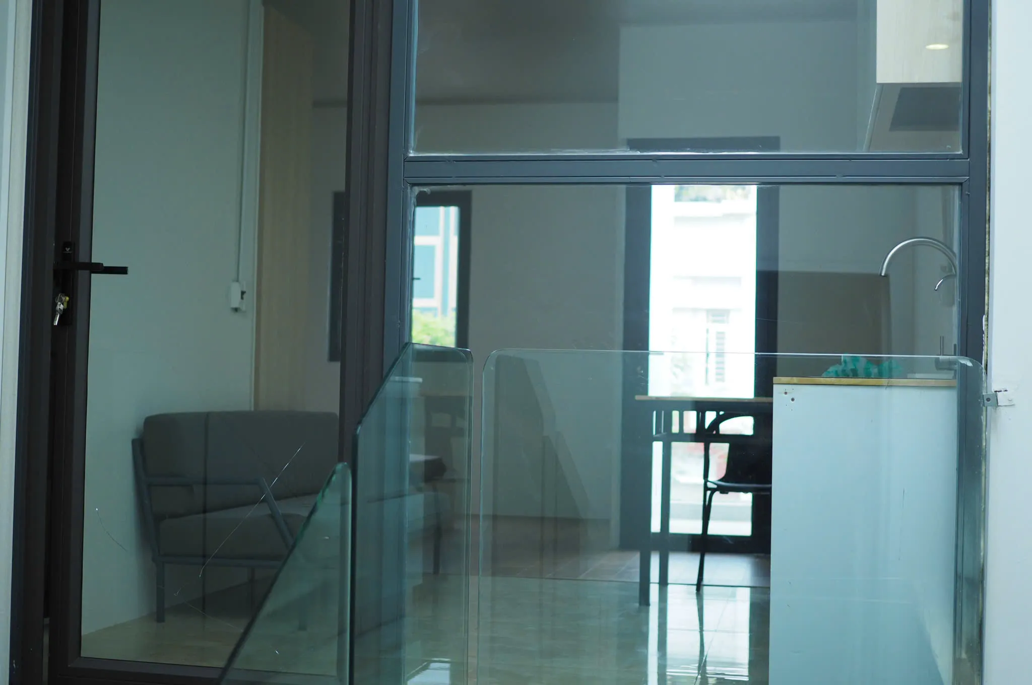 Cửa kính vào studio, sofa và bàn ăn phía trong